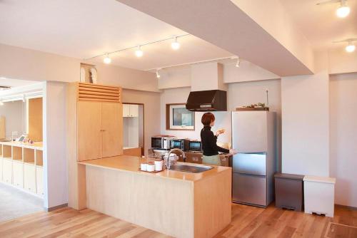 a woman standing in a kitchen with a refrigerator at THE STAY WAKKANAI in Wakkanai