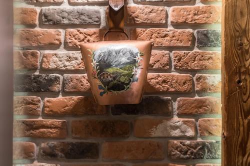 a painting hanging on a brick wall at Villa Adamo & Relax in Zakopane