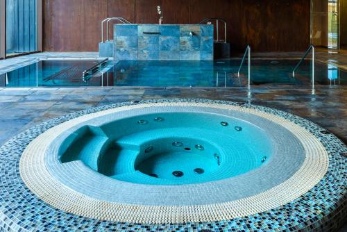 a swimming pool with a blue tub in the middle at Hotel Spa Aguas de los Mallos in Murillo de Gállego