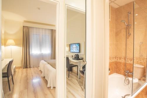 ein Bad mit einer Badewanne und ein Schlafzimmer in der Unterkunft Hotel Pirineos in Figueres