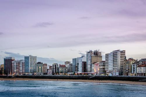 a view of a city with tall buildings and a beach at Hotel Alcomar in Gijón