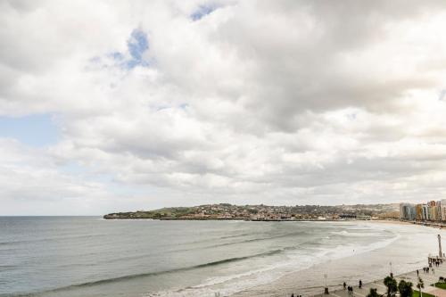 a view of a beach with people standing on the sand at Hotel Alcomar in Gijón
