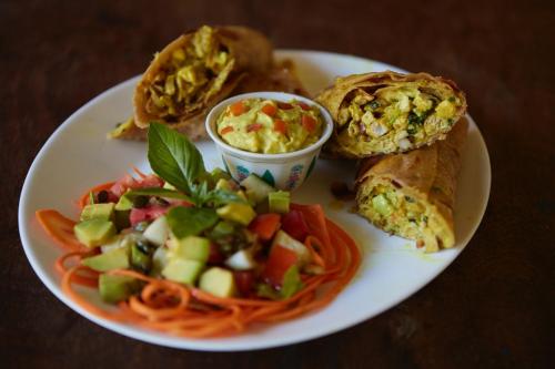 a plate of food with a sandwich and pasta and a salad at Banana House and Wellness Centre in Lamu