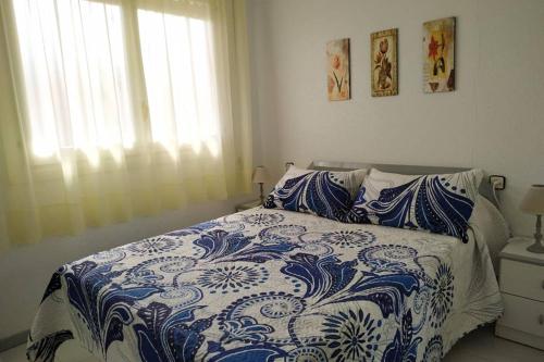 Un dormitorio con una cama azul y blanca y una ventana en Apartamento en Arcos de Font Nova (4-6), en Peñíscola