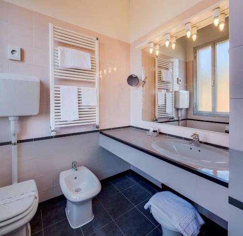 a bathroom with a sink and a toilet and a mirror at Hotel San Donato - Bologna centro in Bologna