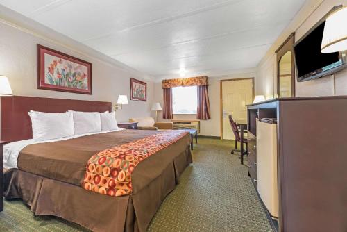 a hotel room with a bed and a flat screen tv at Days Inn by Wyndham Gainesville in Gainesville