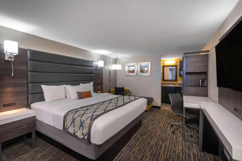 a hotel room with a large bed and a desk at Baymont by Wyndham Murfreesboro in Murfreesboro