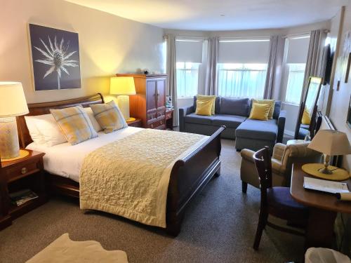 ein Schlafzimmer mit einem Bett, einem Sofa und einem Stuhl in der Unterkunft Mansfield House Hotel in Hawick