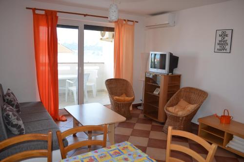 a living room with chairs and a table and a tv at Apartments Leticia in Baška