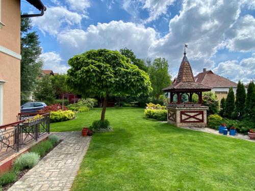 a garden with a gazebo and a tree at Villa Larus in Palić
