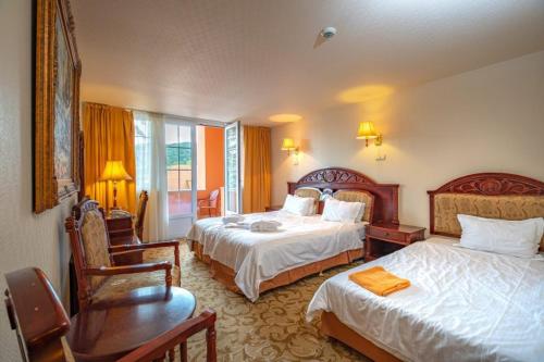 a hotel room with two beds and a desk at Hotel Bellevue Esztergom in Esztergom