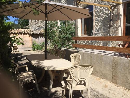 a table and chairs and an umbrella on a patio at Les pieds dans l'eau - Gîte de L'olivier - Plage privée in Blacons