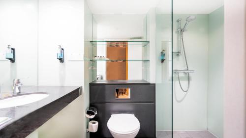 a bathroom with a toilet and a glass shower at Holiday Inn London Luton Airport, an IHG Hotel in Luton