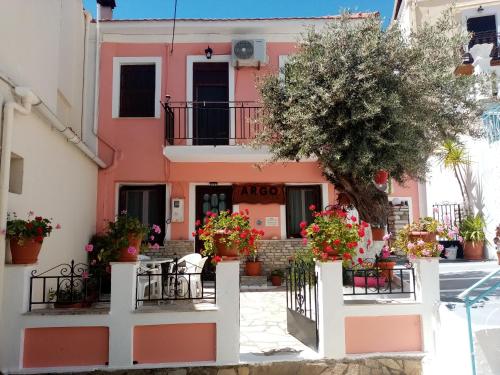 a pink house with flowers in front of it at Αrgo Studios in Pythagoreio