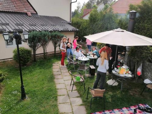 a group of people sitting at tables under an umbrella at Villa Bozovic in Zlatibor