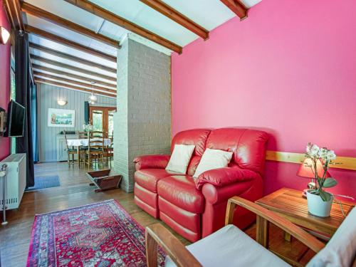 a living room with a red couch and a table at Cozy Chalet in Trois Ponts with Forest Near in Trois-Ponts