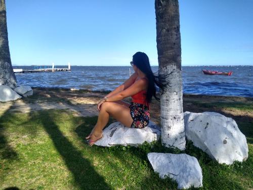 a woman sitting on a rock next to a tree at Casa com piscina in Araruama