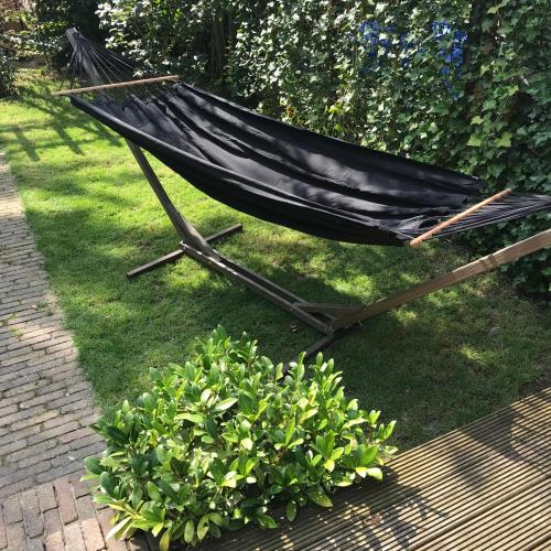 a hammock sitting in the grass next to a bush at B&B Logeren bij Lies in Harderwijk