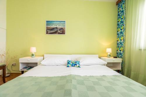 um quarto com uma grande cama branca com duas mesas de cabeceira em Muzic Budget Double Room em Mali Lošinj