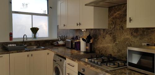 a kitchen with white cabinets and a stove top oven at Auld Leigh-Lann Apartments in Anstruther