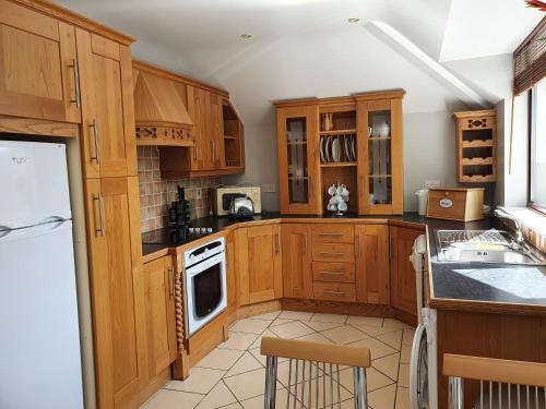 a kitchen with wooden cabinets and a white refrigerator at AbbeyCourt Kenmare Kerry in Kenmare