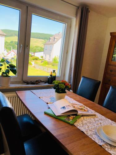 a dining room table with a book and a window at Ferienwohnung Kleine Auszeit in Maring-Noviand