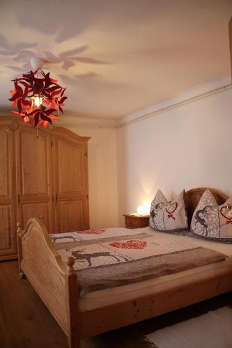 a bedroom with a wooden bed and a chandelier at Buchschneider - Ferienhaus Maier - Landhof in Schwarzautal