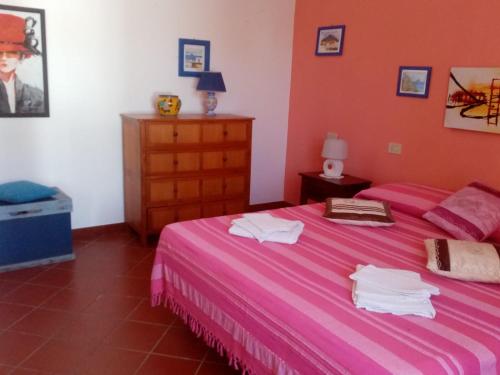 a bedroom with a pink bed with towels on it at Agriturismo SoleMare in Stromboli