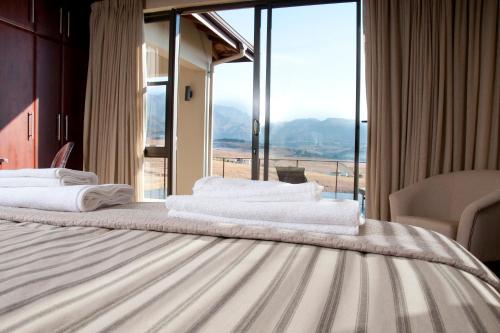a hotel room with a bed with a large window at Cathkin Haven in Champagne Valley
