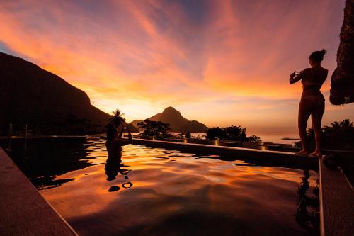 a man and a woman standing on the edge of a swimming pool at Frendz Hostel El Nido in El Nido