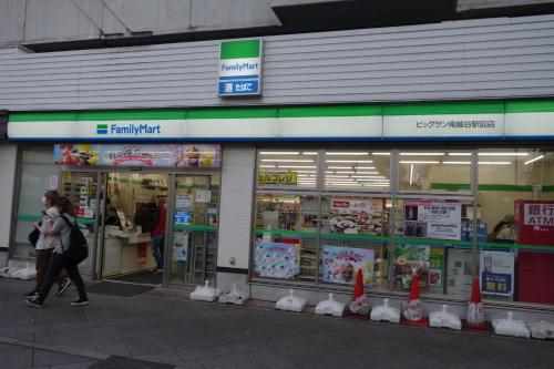 a woman walking in front of a store at Taro's Hostel Minami Koshigaya in Koshigaya