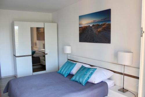 sypialnia z łóżkiem z niebiesko-białymi poduszkami w obiekcie Apartament na Polankach Kołobrzeg w Kołobrzegu