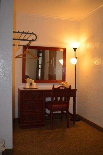 a bathroom with a desk with a mirror and a lamp at The Evergreen Motel in Kansas in Pratt