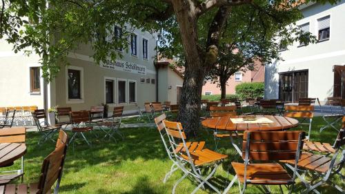 an outdoor patio with tables and chairs under a tree at Gasthaus Schöllmann in Feuchtwangen