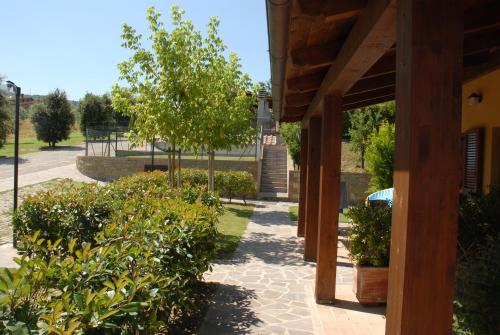 a walkway with trees and bushes next to a building at Agriturismo Tenuta Badia in Paciano