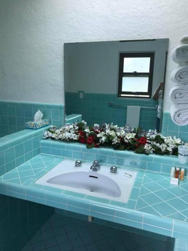 a bathroom with a sink and a mirror and flowers at The Evergreen Motel in Kansas in Pratt