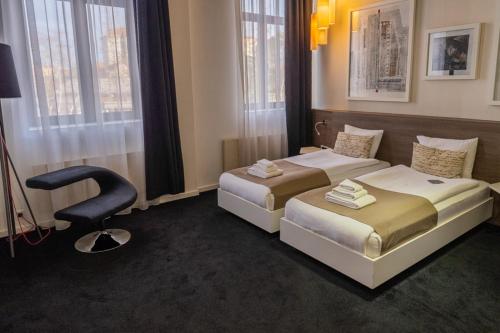 a hotel room with two beds and a chair at Garni Hotel Eter in Niš