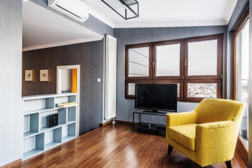 a living room with a yellow chair and a television at Triton Park Apartments in Warsaw