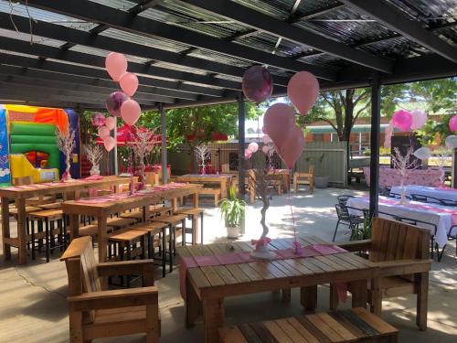 a patio with wooden tables and pink balloons at Riverina hotel in Holbrook