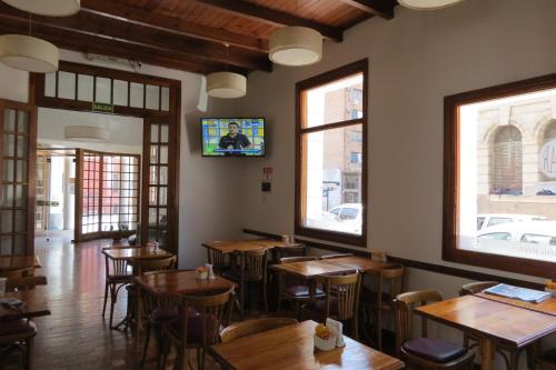 un restaurante con mesas de madera y TV en la pared en Gran Rex Hotel en Córdoba