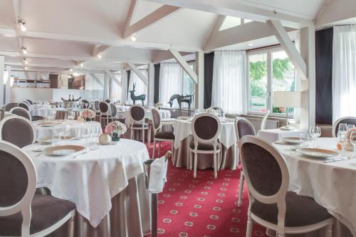 a dining room with white tables and chairs at Hôtel & Restaurant Le Relais d'Aumale in Chantilly