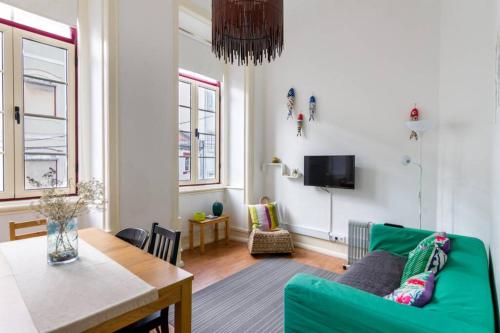 a living room with a green couch and a table at Cozy apartment at the city center in Figueira da Foz