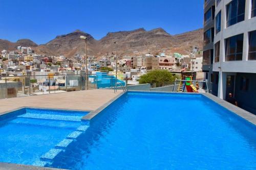 a swimming pool on the roof of a building with a city at Mindelo Apartments in Mindelo