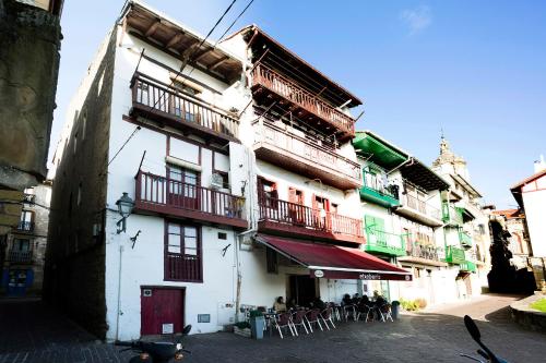a white building with balconies and tables and chairs at Txoriak - Basquenjoy in Hondarribia