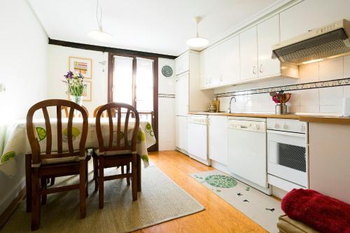 a kitchen with white cabinets and a table and chairs at Txoriak - Basquenjoy in Hondarribia