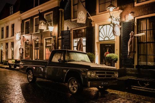 an old truck parked on a street at night at Boutique Hotel Elburg met Tapperij in Elburg