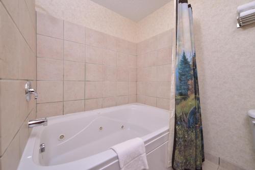 a white bath tub in a bathroom with a shower at Kelly Inn and Suites Mitchell in Mitchell