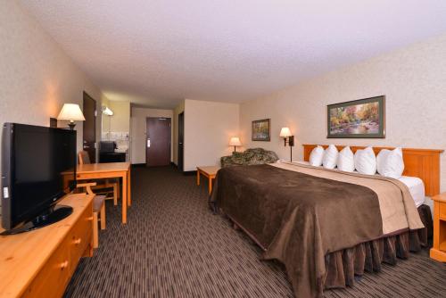 a hotel room with a bed and a flat screen tv at Kelly Inn and Suites Mitchell in Mitchell