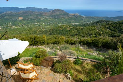a patio with two chairs and an umbrella at Traditional Windmill-Milos in Kroústas