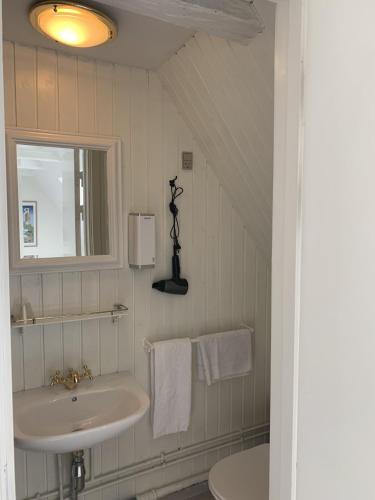 a white bathroom with a sink and a mirror at Den Gamle Arrest in Ribe